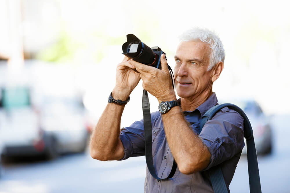 Older man taking a picture outside